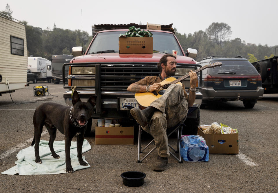 Grayson Howard plays the guitar while helping friends who evacuated to the the Green Valley Community Church evacuation shelter on Thursday, Aug. 19, 2021, in Placerville, Calif., as the Caldor Fire continues to burn. (AP Photo/Ethan Swope)