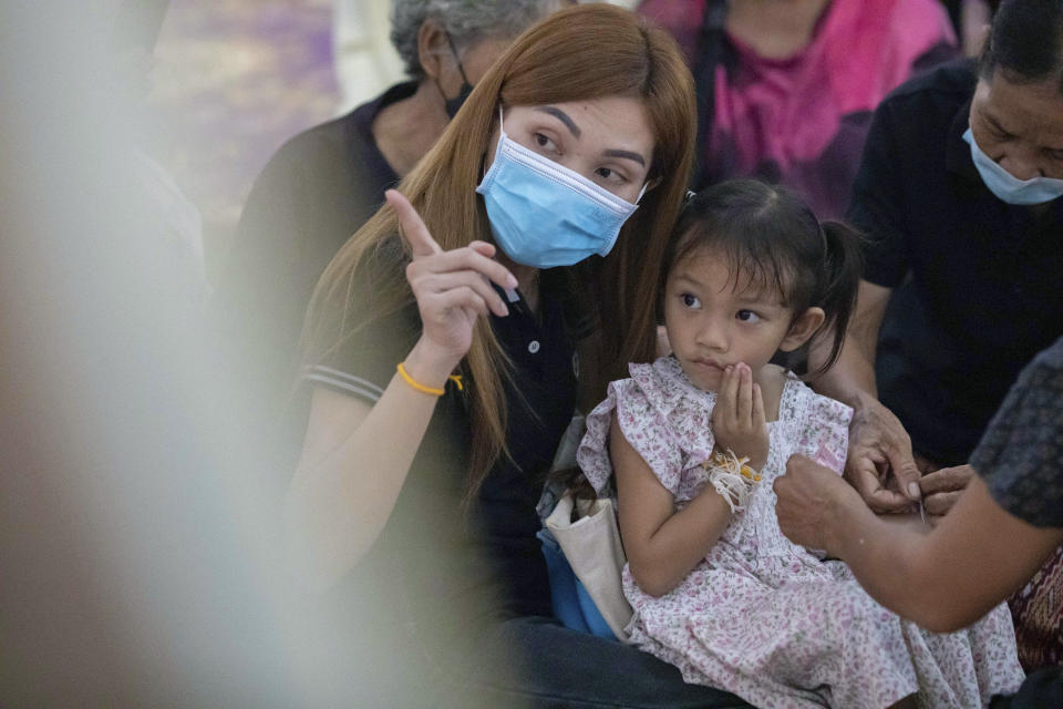 Paweenuch Supolwong, 3, the only child to emerge unscathed from the mass killing attack at the day care center, and her mother Anonpai Srithong, 35, join a Buddhist ceremony inside Wat Rat Samakee temple in Uthai Sawan, north eastern Thailand, Saturday, Oct. 8, 2022. A former police officer burst into a day care center in northeastern Thailand on Thursday, killing dozens of preschoolers and teachers before shooting more people as he fled. (AP Photo/Wason Wanichakorn)