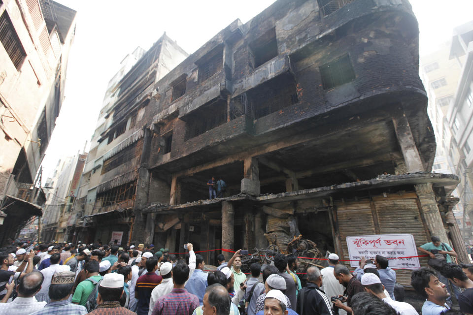 People gather outside the site of Wednesday night's fire in Dhaka, Bangladesh, Friday, Feb. 22, 2019. Police on Friday were seeking up to a dozen suspects in connection with a fire in the oldest part of Bangladesh's capital that killed scores of people. (AP Photo/Mahmud Hossain Opu )