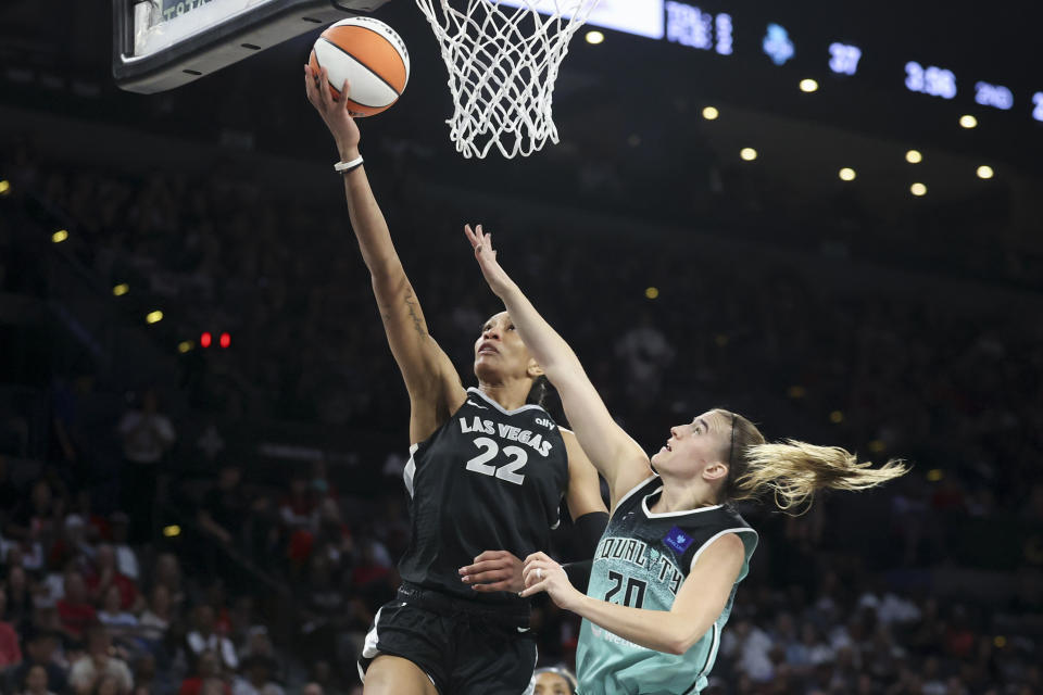 Las Vegas Aces center A'ja Wilson (22) goes up for a basket over New York Liberty guard Sabrina Ionescu (20) during the first half of a WNBA Semifinal basketball game, Sunday, Oct. 6, 2024, in Las Vegas. (AP Photo/Ian Maule)