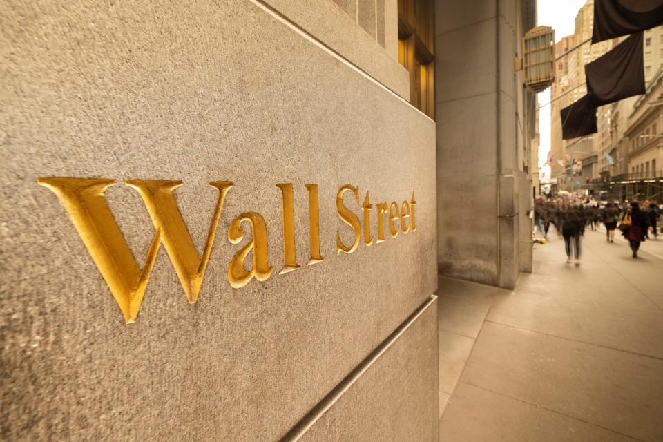 The words, Wall Street, engraved in gold coloring on the side of a building. 