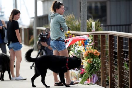 People stop to pause over a makeshift memorial near Truth Aquatics as the search continues for those missing in a pre-dawn fire that sank a commercial diving boat off Santa Barbara, California