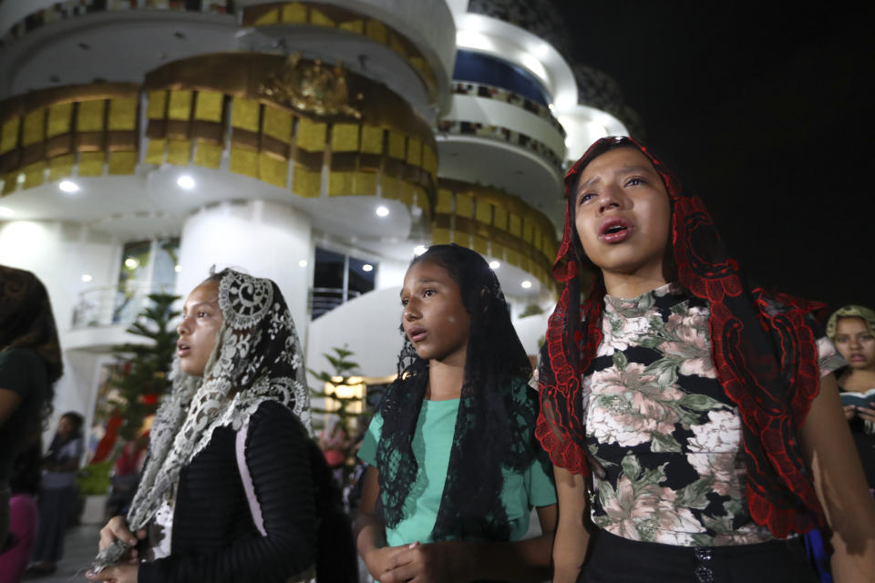 ADDS FIRST NAME - Young women pray outside the "La Luz Del Mundo," or Light of the World church, after members learned their church's leader Naasón Joaquín García was arrested in the U.S., in Guadalajara, Mexico, Tuesday, June 4, 2019. California authorities have charged Garcia, the self-proclaimed apostle of the Mexico-based church that claims over 1 million followers, with child rape, human trafficking and producing child pornography in Southern California. (AP Photo/Refugio Ruiz)