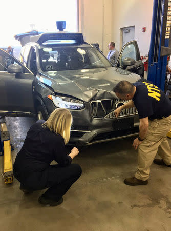 National Transportation Safety Board (NTSB) investigators examine a self-driving Uber vehicle involved in a fatal accident in Tempe, Arizona, U.S., March 20, 2018. A women was struck and killed by the vehicle on March 18, 2018. National Transportation Safety Board/Handout via REUTERS