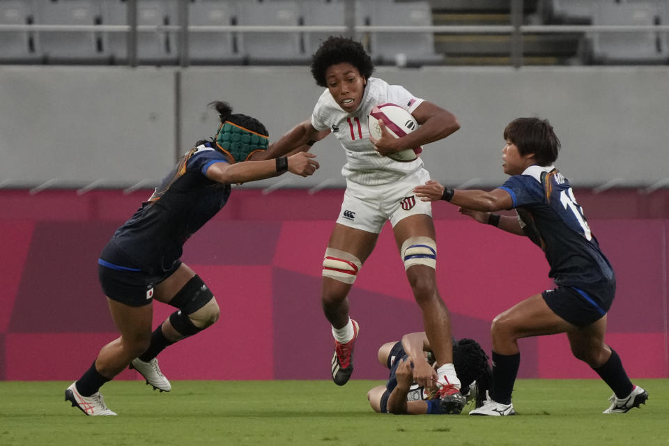 Kris Thomas of the United States comes under pressure from Japan's Marin Kajiki, left, Mio Yamanaka, right, and Hana Nagata in their women's rugby sevens match at the 2020 Summer Olympics, Thursday, July 29, 2021 in Tokyo, Japan. (AP Photo/Shuji Kajiyama)