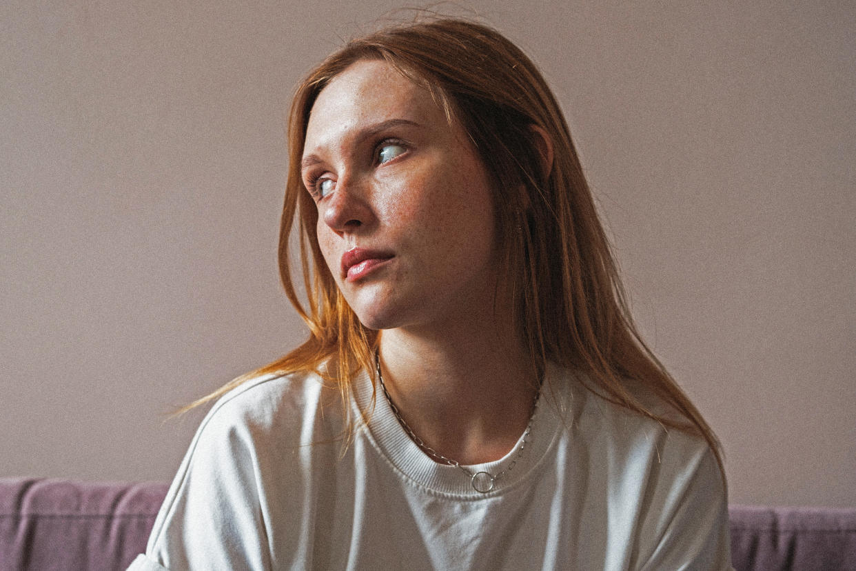 A pensive red-haired adolescent girl in a T-shirt