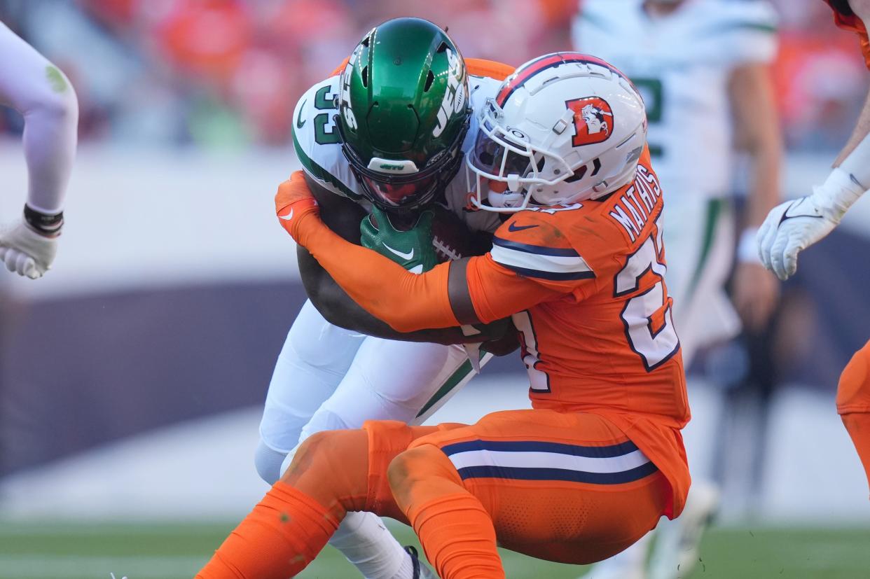 Denver Broncos cornerback Damarri Mathis (27) tackles New York Jets running back Dalvin Cook during an Oct. 8, 2023 game at Empower Field at Mile High.