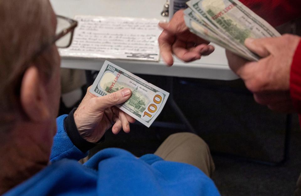 A Secret Santa elf hands someone a $100 bill during the annual Secret Santa in Lincoln Park on Thursday, Dec. 14, 2023.