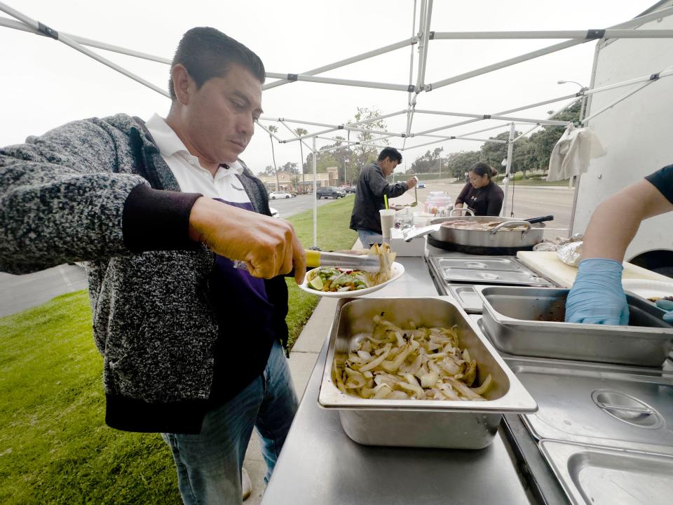 Victor Morales, of Oxnard, adds a grilled onions to his tacos at the sidewalk taqueria on Eastman Avenue in Ventura near the Burlington Coat Factory store on May 19.