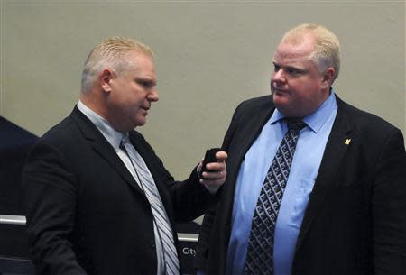Toronto Mayor Rob Ford (R) speaks with his brother Councillor Doug Ford during a city council meeting in Toronto November 15, 2013. REUTERS/Jon Blacker