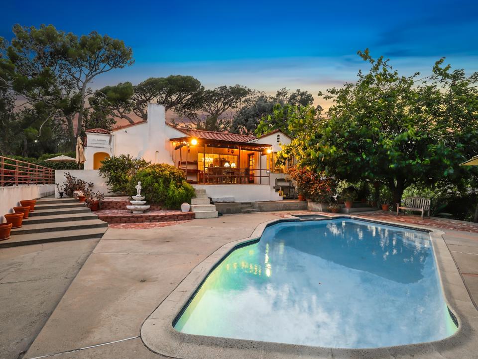 The view from the backyard of the house showing the pull and trees surrounding the home. 