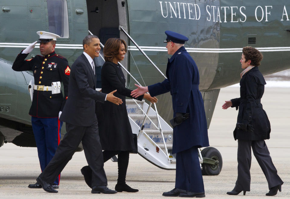 A Marine salutes as President Barack Obama and first lady Michelle Obama are greeted by 89th Airlift Wing Commander Col. David Almand and his wife Cathy Almand at Andrews Air Force Base, Md., Friday, March 7, 2014, before boarding Air Force One for a trip to Florida. (AP Photo/Jacquelyn Martin)