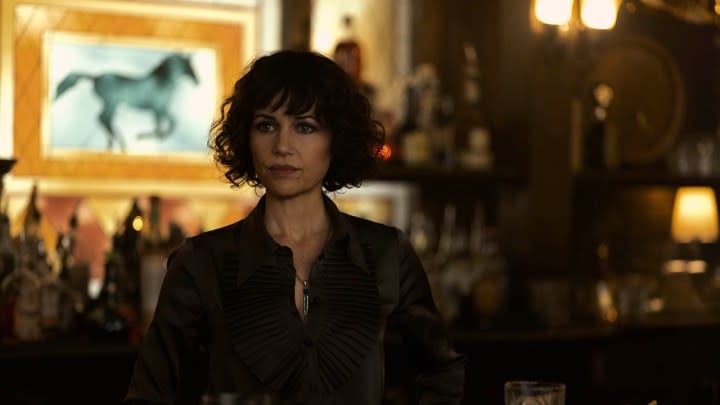 Carla Gugino sitting at a table in a scene from The Fall of the House of Usher.