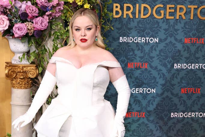 Nicola Coughlan posing in an elegant off-the-shoulder gown with structured details and gloves at the 'Bridgerton' Netflix event