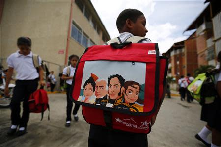 A student carrying a backpack bearing the image of national independence hero Simon Bolivar (2nd R), walks as they leave the school in Ciudad Caribia outside Caracas September 19, 2013. REUTERS/Jorge Silva