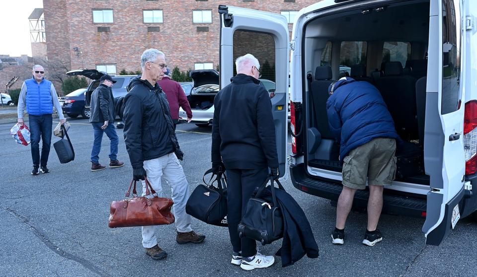 A group of former athletes and coaches from MetroWest schools board a van at the Sheraton Framingham Hotel to attend the Army/Navy football game, Dec. 9, 2022.  