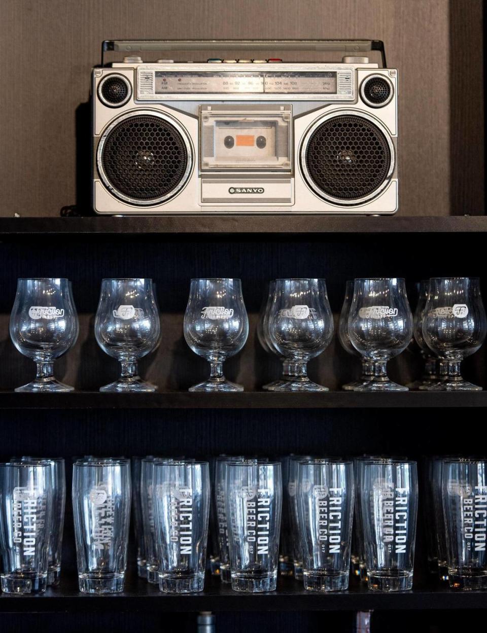 Beer glasses and a boombox line a shelf behind the bar at Friction Beer Co.