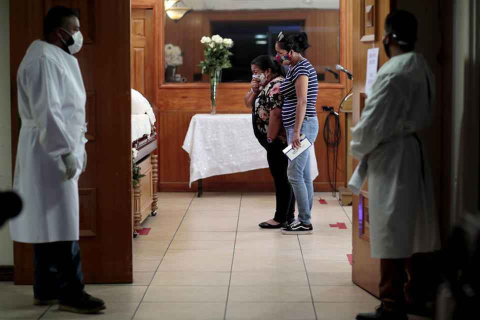 Iris Martinez weeps as she stands 3 feet from her father's casket while her best friend comforts her in Los Angeles on Aug. 5.