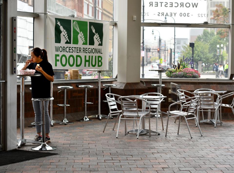 Nguyen Duong of Worcester enjoys an empanada at the new Worcester Regional Food Hub location at the corner of Main and Pleasant streets in Worcester. She is an employee at Coco Vibez.