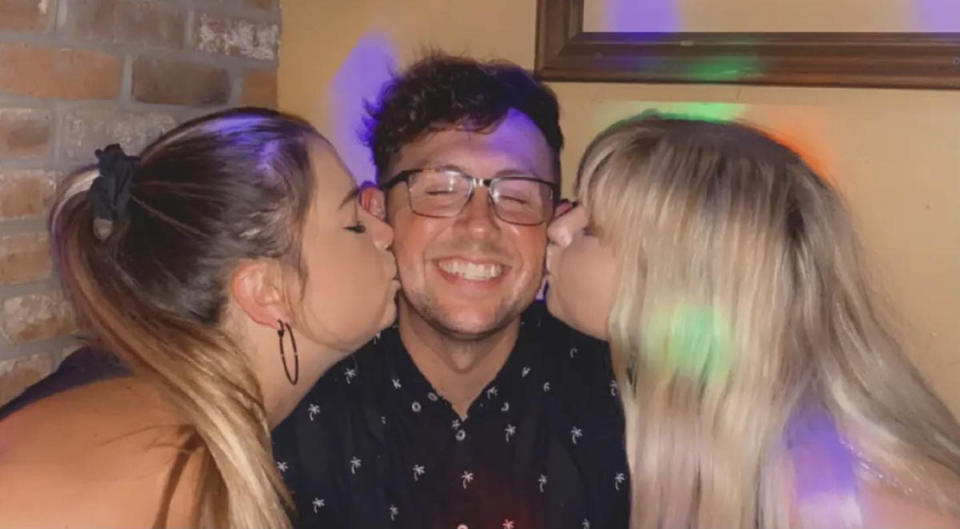 The throuple take a photo together with both women kissing the man's cheeks