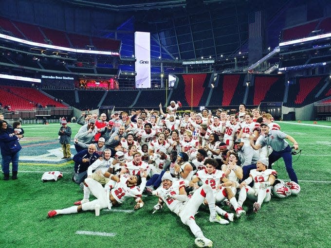 Milton football players and coaches pose with the trophy after winning the 2018 GHSA 7A state championship against Colquitt County.