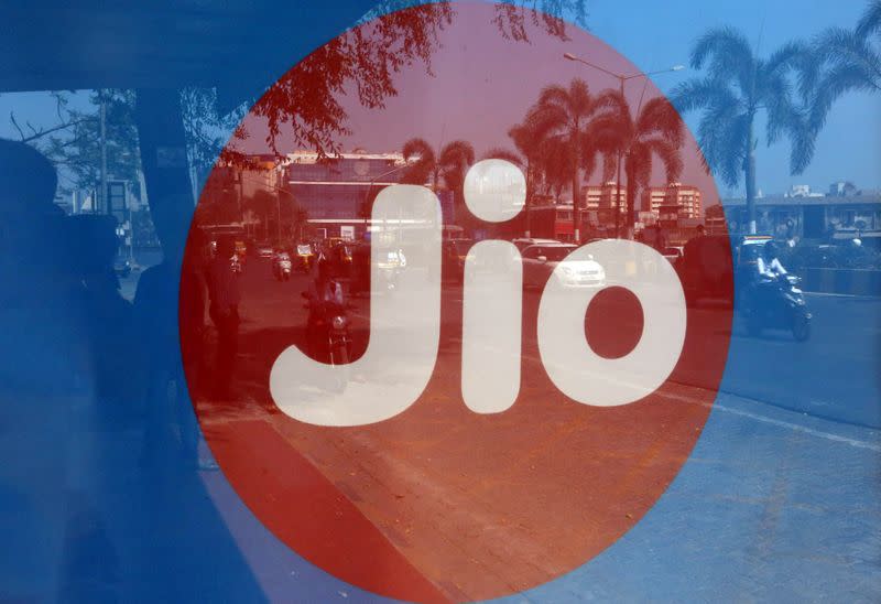 FILE PHOTO: Commuters are reflected on an advertisement of Reliance Industries' Jio telecoms unit, at a bus stop in Mumbai