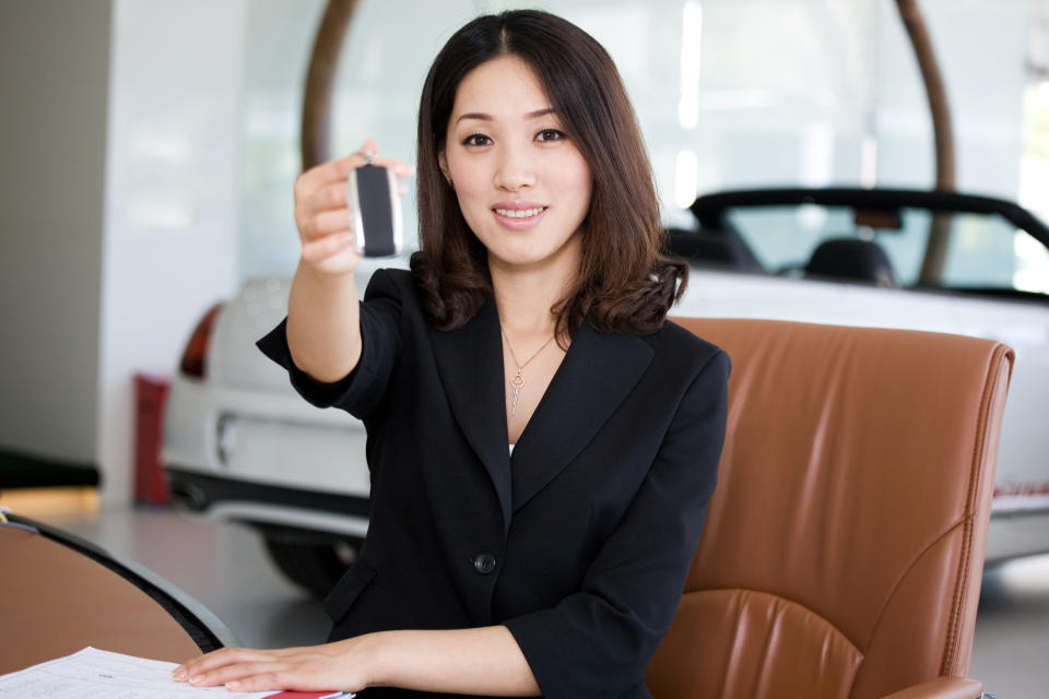 A auto dealer representative hands over the keys to a car.