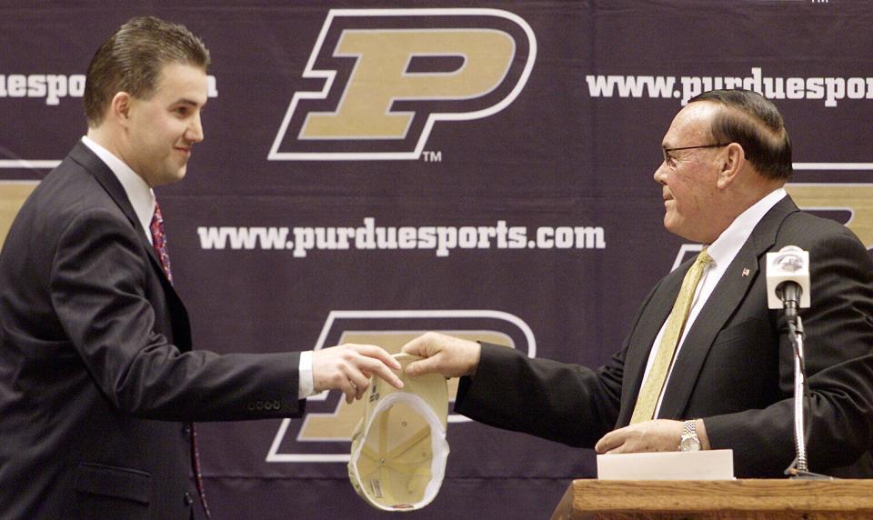 Purdue basketball coach Gene Keady right passes a Purdue hat to Matt Painter at Mackey Arena in West Lafayette, Indiana, on April 9 2004. Painter, who played at Purdue from 1989-93, resigned as head basketball coach of Southern Illinois so he could return to his alma mater as an associate coach and the eventual successor to his former coach.