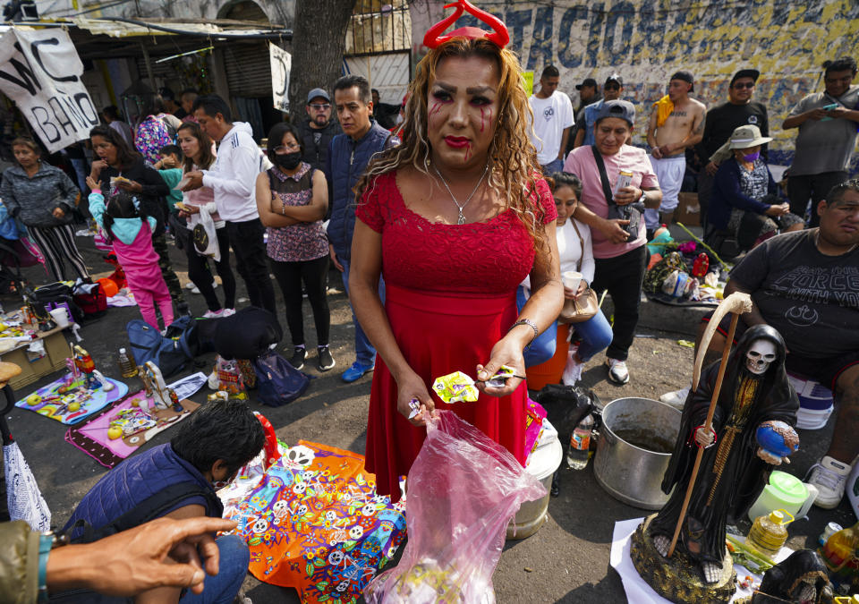 Una creyente regala dulces a quienes esperan para entrar al altar de "La Santa Muerte", en el barrio de Tepito de la Ciudad de México, el martes 1 de noviembre de 2022. La Santa Muerte es una imagen de culto y un santo popular, una personificación de la muerte, asociada con la curación, la protección y la entrega segura al más allá por parte de sus devotos. (AP Foto/Fernando Llano)