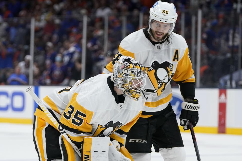 Pittsburgh Penguins' Kris Letang (58) consoles Pittsburgh Penguins goaltender Tristan Jarry (35) during the second period of Game 6 of an NHL hockey Stanley Cup first-round playoff series against the New York Islanders, Wednesday, May 26, 2021, in Uniondale, N.Y. (AP Photo/Frank Franklin II)