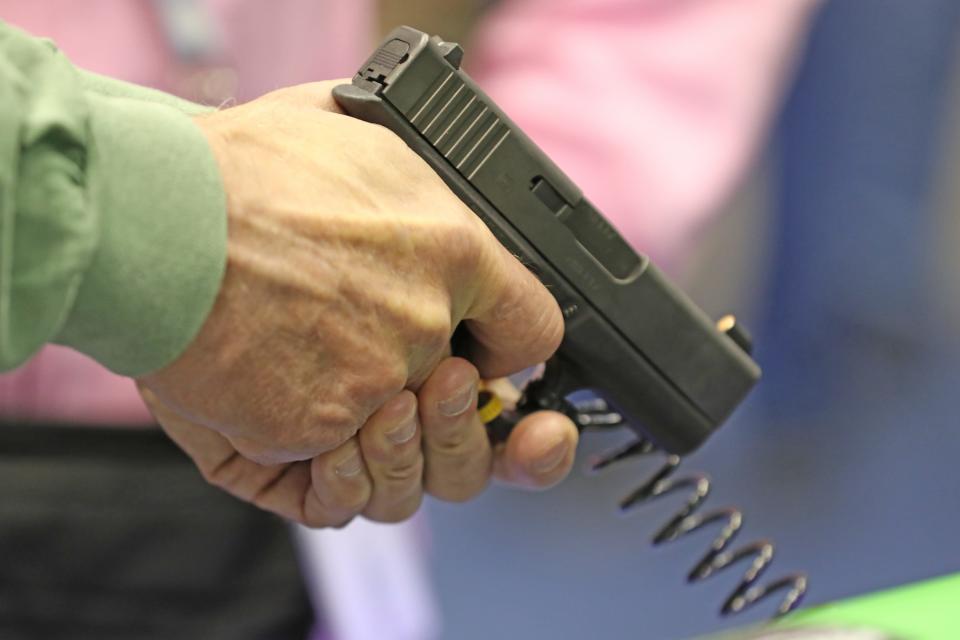 A customer at the 2019 NRA Annual Meetings & Exhibits in Indianapolis tests out the grip on a handgun on Friday, April 26, 2019. 