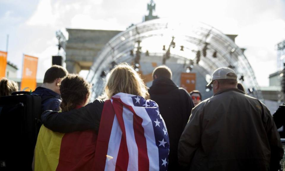 Two women carrying a German and US flag wait for Obama and Merkel to appear on stage.