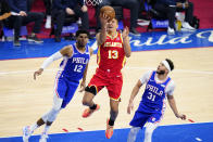 Atlanta Hawks' Bogdan Bogdanovic, center, goes up for a shot between Philadelphia 76ers' Tobias Harris, left, and Seth Curry during the second half of Game 5 in a second-round NBA basketball playoff series, Wednesday, June 16, 2021, in Philadelphia. (AP Photo/Matt Slocum)