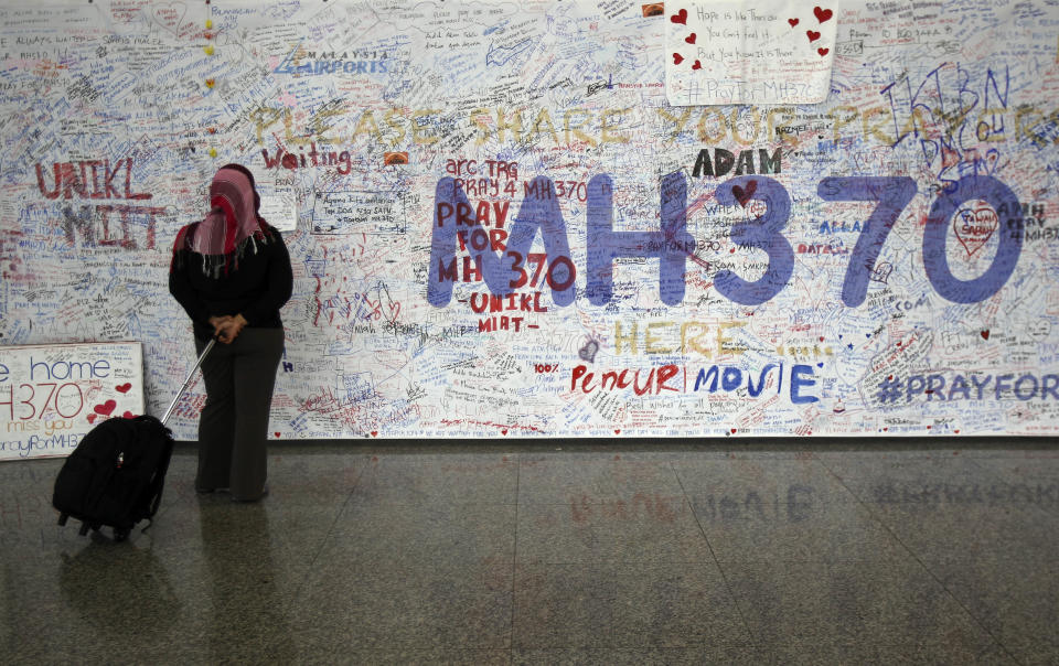 FILE - In this March 18, 2014 file photo, a woman reads messages for passengers aboard a missing Malaysia Airlines plane, at Kuala Lumpur International Airport in Sepang, Malaysia. Solving the mystery of the missing Malaysian plane is proving to be as easy as cracking a homicide without a body, witness or motive. All while billions of people are waiting for the kind of quick and clear resolution that we’ve come to expect in the information age _ and speculating in sometimes wild ways when that resolution doesn’t come. (AP Photo/Lai Seng Sin, File)