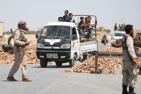 Syria Democratic Forces (SDF) fighters man a checkpoint as civilians on pick-up trucks evacuate from the southern districts of Manbij city after the SDF advanced into it in Aleppo Governorate, Syria, July 1, 2016. REUTERS/Rodi Said