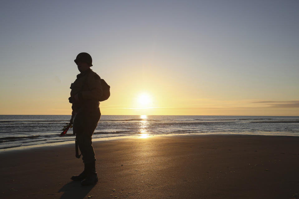 World War II enthusiast stands on the beach at dawn on Omaha Beach, Normandy, Sunday, June 6, 2021, the day of 77th anniversary of the assault that helped bring an end to World War II. While France is planning to open up to vaccinated visitors starting next week, that comes too late for the D-Day anniversary. So for the second year in a row, most public commemoration events have been cancelled. (AP Photo/David Vincent)