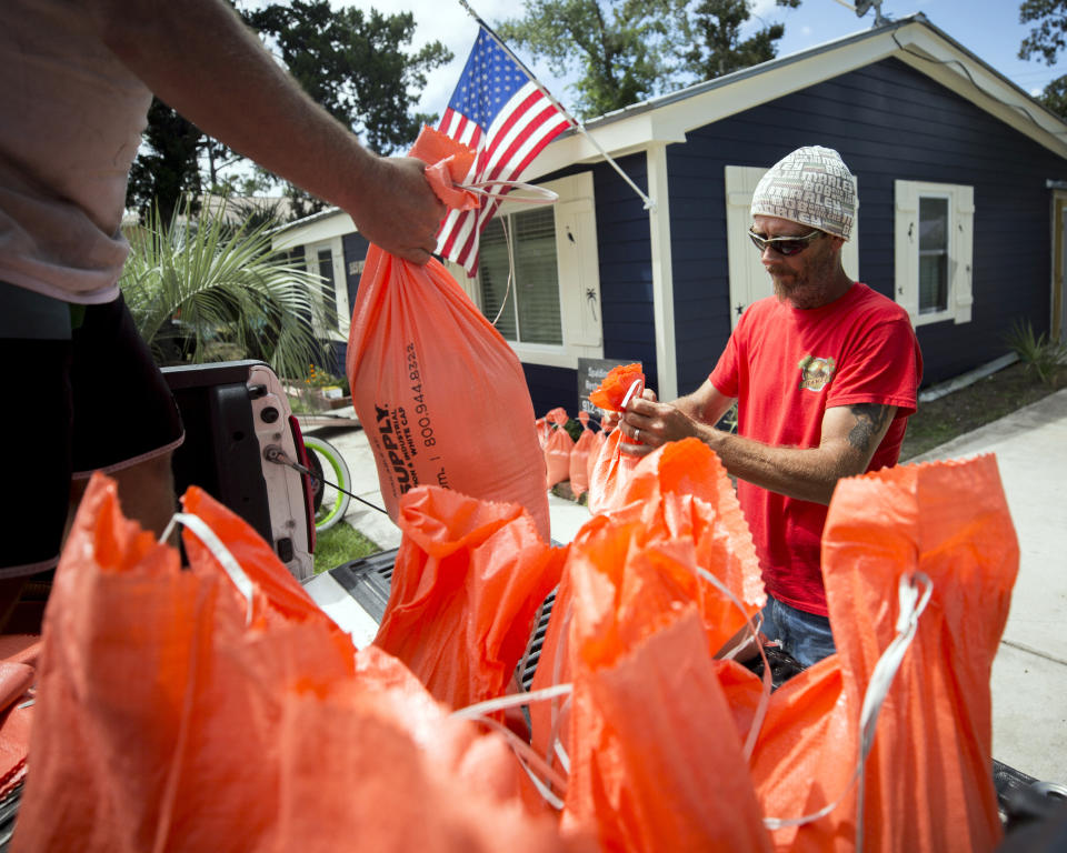 Tom Sikes, right, helps his friend Joey Spalding, left, fill sandbags at Spalding's home in Tybee Island, Ga., Tuesday, Sept. 3, 2019, before the potential arrival of Hurricane Dorian. Spalding's home was flooded by Hurricane Irma last year when he got three feet of water from the storm surge. (AP Photo/Stephen B. Morton)
