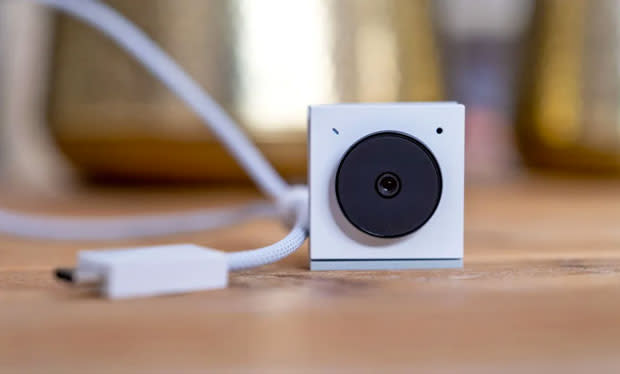 Image of the Opal Tadpole webcam on a brown desk with its white, braided USB-C cable beside it. 