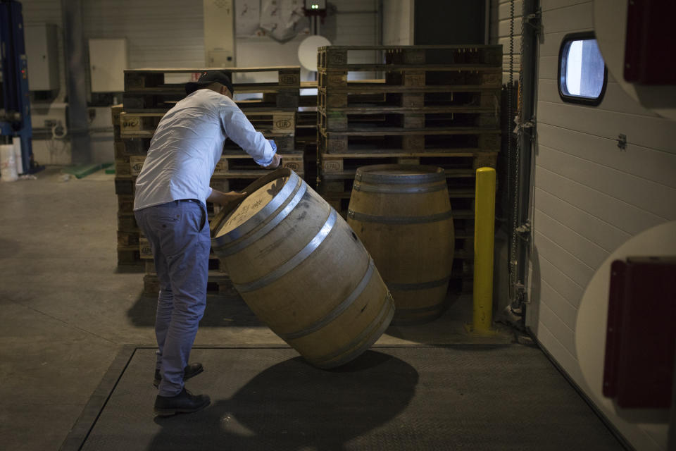 An employee moves an empty barrel in the shipping warehouse of the French wine producer MDCV, in the Chateau des Bertrands in Le Cannet-des-Maures, in the Provence region, Thursday Oct. 10, 2019. European producers of premium specialty agricultural products like those protected at home for their territorial origin and sometimes centuries of artisanal know-how that fetch premium prices like French wine, are facing a U.S. tariff hike on Friday, dragged into a trade war over the fiercely competitive aerospace industry.(AP Photo/Daniel Cole)