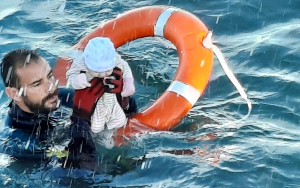 A member of the Spanish Guardia Civil holding a migrant baby in the water off the shore of the Spanish enclave of Ceuta - SPANISH GUARDIA CIVIL /REUTERS