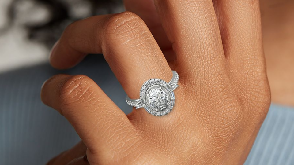 This exaggerated antique-inspired oval-cut engagement ring has baguette-style diamonds on the platinum band.