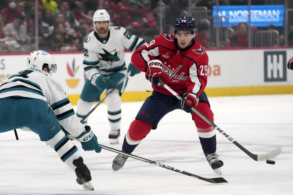 Washington Capitals center Hendrix Lapierre (29) passes the puck around San Jose Sharks defenseman Kyle Burroughs (4) in the first period of an NHL hockey game, Sunday, Oct. 29, 2023, in Washington. (AP Photo/Mark Schiefelbein)