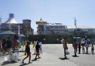 Families walk into the Santa Monica Beach in Santa Monica, Calif., Wednesday, March 31, 2021. Health officials in California and across the country are urging caution because of a troubling rise in new cases of COVID-19, but aquariums and amusement parks are on track to reopen in California anyway. The Pacific Park on the Santa Monica Pier has announced it is preparing to reopen its rides but has only said it expects that to happen sometime after April 1. (AP Photo/Damian Dovarganes)