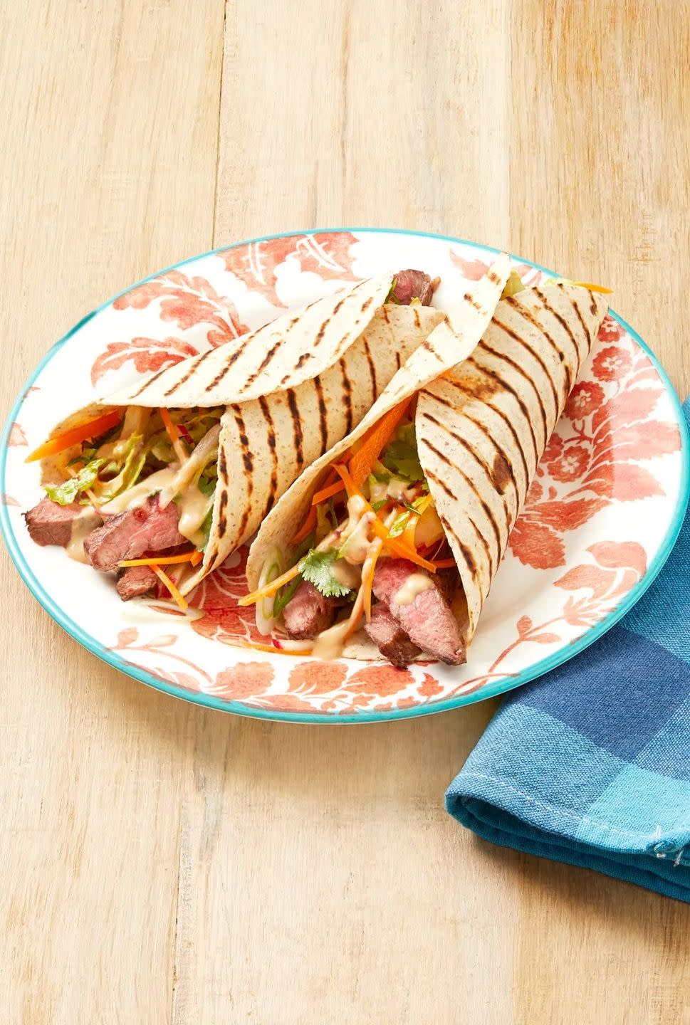 grilled steak wraps with peanut sauce on red floral plate