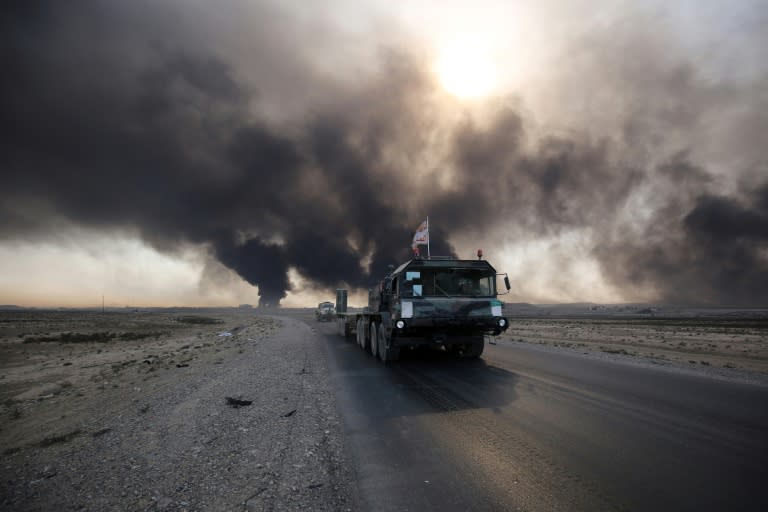 Iraqi army vehicle drives down a road east of Mosul, northern Iraq, on October 22, 2016, as displaced families flee areas of unrest during an operation to retake the city from Islamic State (IS) group jihadists