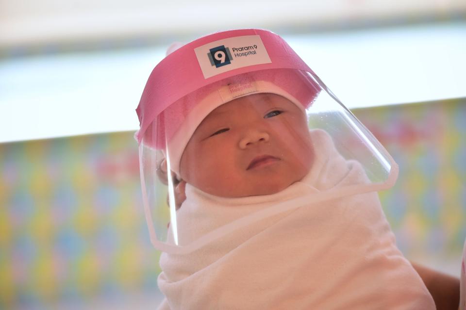 A newborn baby wearing a face shield at a hospital in Bangkok. (Photo: LILLIAN SUWANRUMPHA via Getty Images)