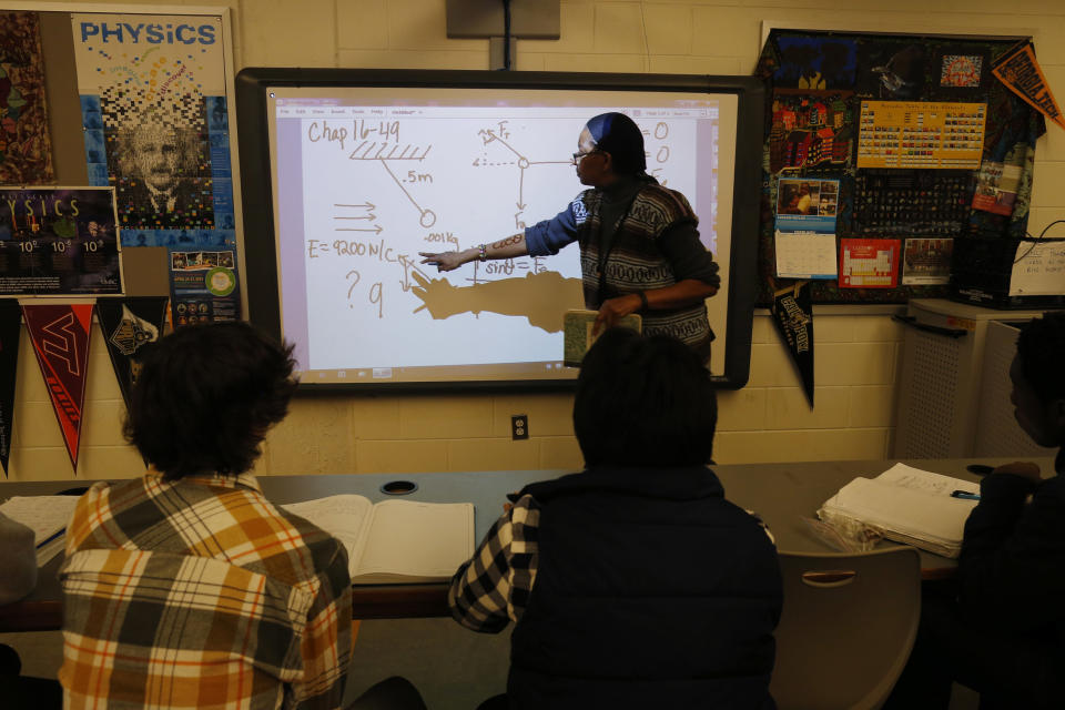 Teacher Angela Benjamin works with students in the Advanced Placement (AP) Physics class at Woodrow Wilson High School in Washington, Friday, Feb. 7, 2014. The College Board says in a new report that the number of U.S. public students taking Advanced Placement classes doubled over the last decade. The class of 2013 of took 3.2 million AP exams. (AP Photo/Charles Dharapak)