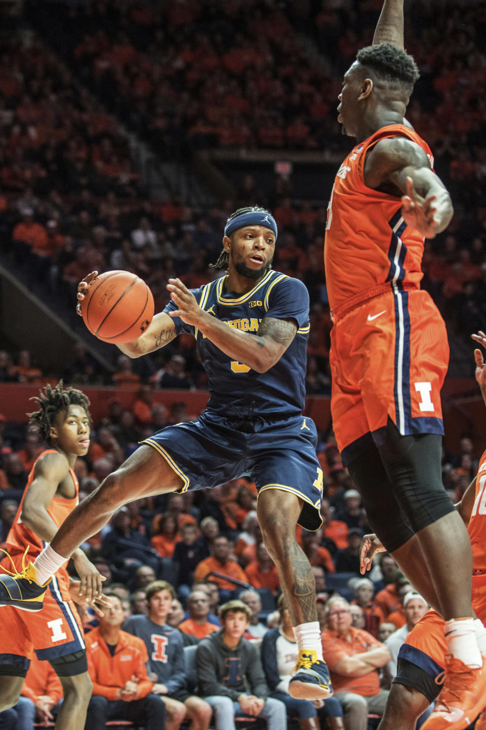 Michigan's Zavier Simpson (3) passes around Illinois defender Kofi Cockburn (21) in the second half of an NCAA college basketball game, Wednesday, Dec. 11, 2019, in Champaign, Ill. (AP Photo/Holly Hart)