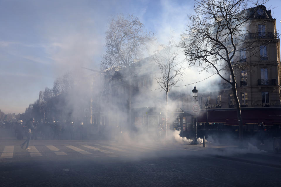 Tear gas grenades a fired during a protest on the Champs-Elysees avenue, Saturday, Feb.12, 2022 in Paris. Paris police intercepted at least 500 vehicles attempting to enter the French capital in defiance of a police order to take part in protests against virus restrictions inspired by the Canada's horn-honking "Freedom Convoy." . (AP Photo/Adrienne Surprenant)