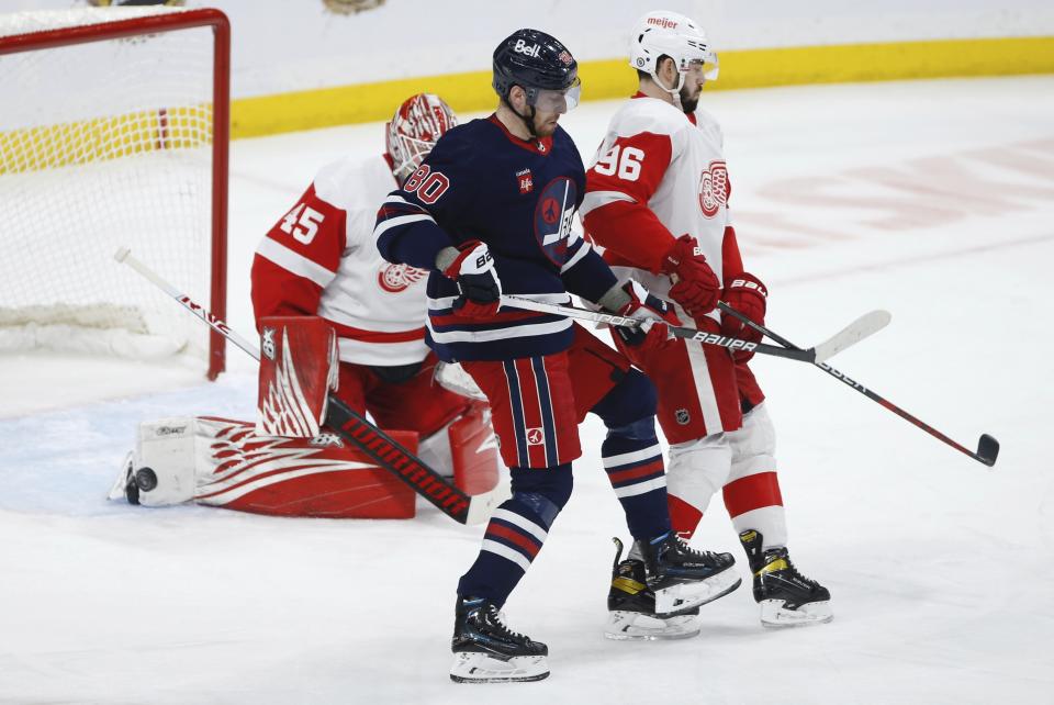 Winnipeg Jets' Kyle Connor's (not shown) scores against Detroit Red Wings goaltender Magnus Hellberg (45) as Jets' Pierre-Luc Dubois (80) and Red Wings' Jake Walman (96) fight for position during first-period NHL hockey game action in Winnipeg, Manitoba, Friday, March 31, 2023. (John Woods/The Canadian Press via AP)